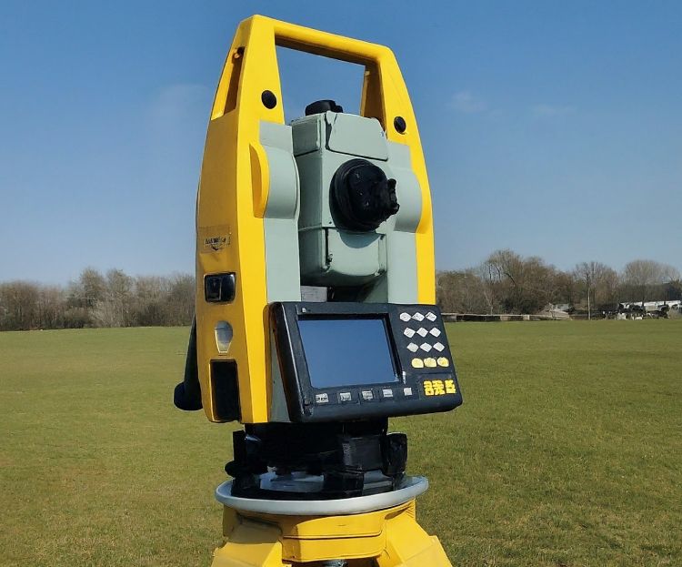 A Total Station surveying equipment set up in a field.